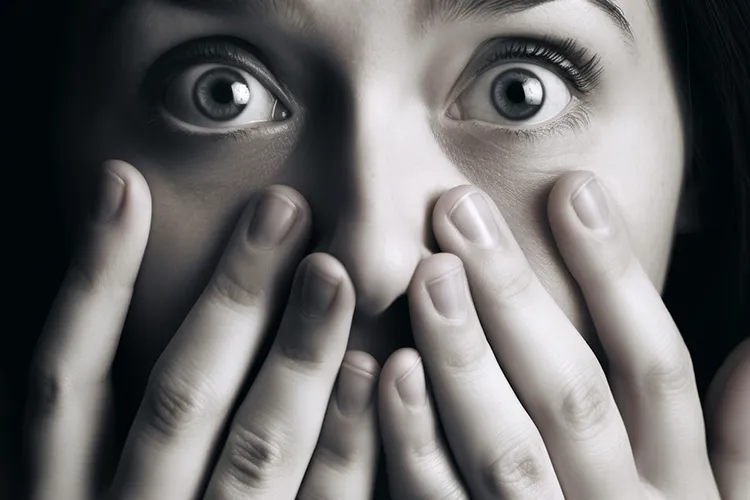 Scared woman who has covered her face with her hands